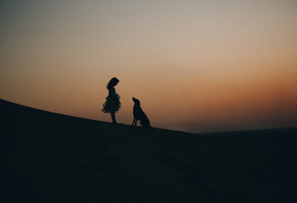 Silhouette of a girl and her dog in the sand dunes of Dubai and Abu Dhabi