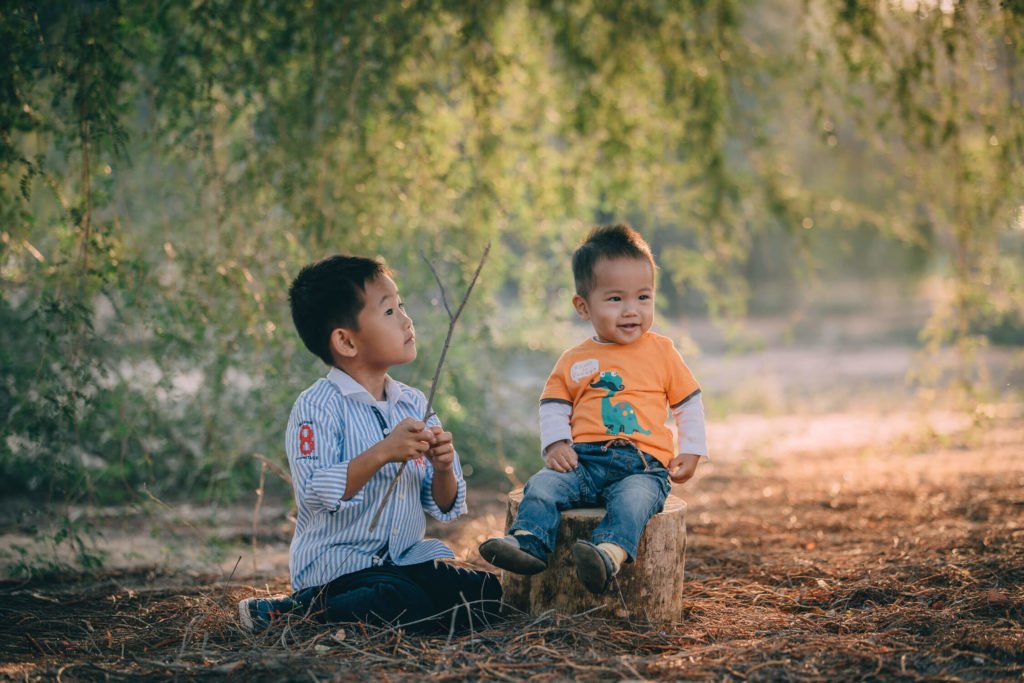 Two little Chinese boys sitting in the beach in Dubai