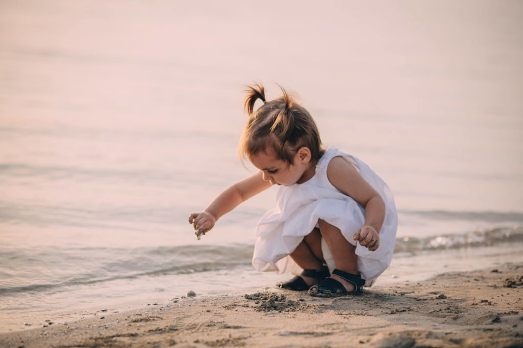 Little girl with white dress plays in the shore of the beach in Dubai and Abu Dhabi