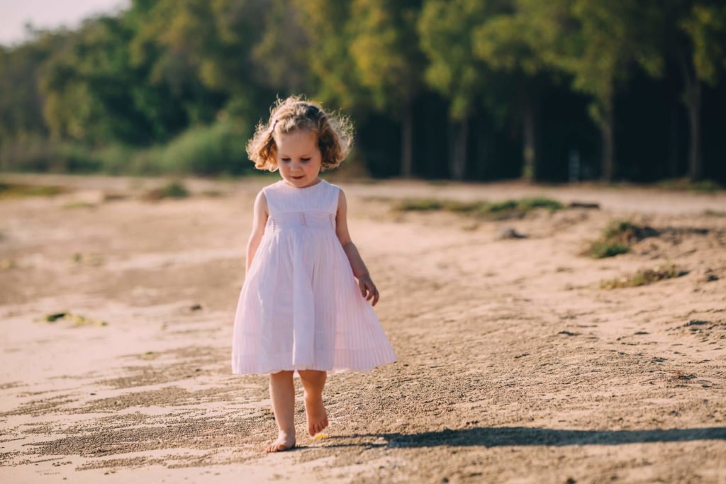 Little girl walking with her pink dress in the beach of Dubai