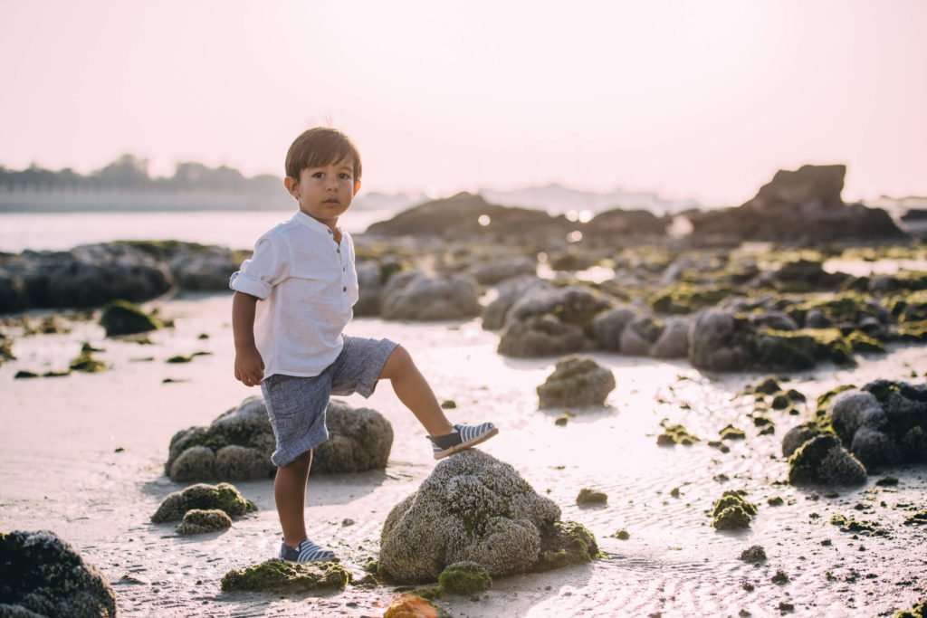 Boy plays in the stones near the beach shore of Abu Dhabi