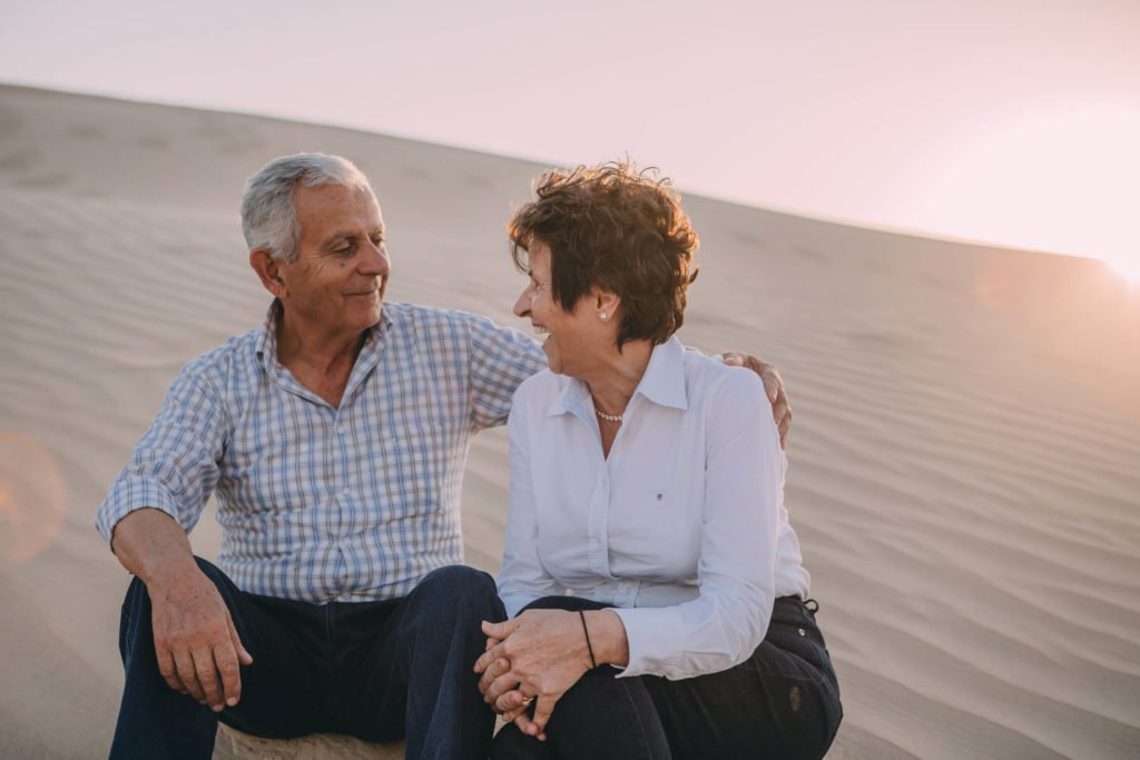 Mature couple laugh in the sand dunes of the desert in Dubai