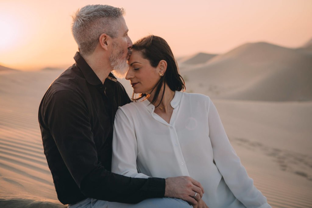 A man kisses his wife´s forehead in the sand dunes of Abu Dhabi