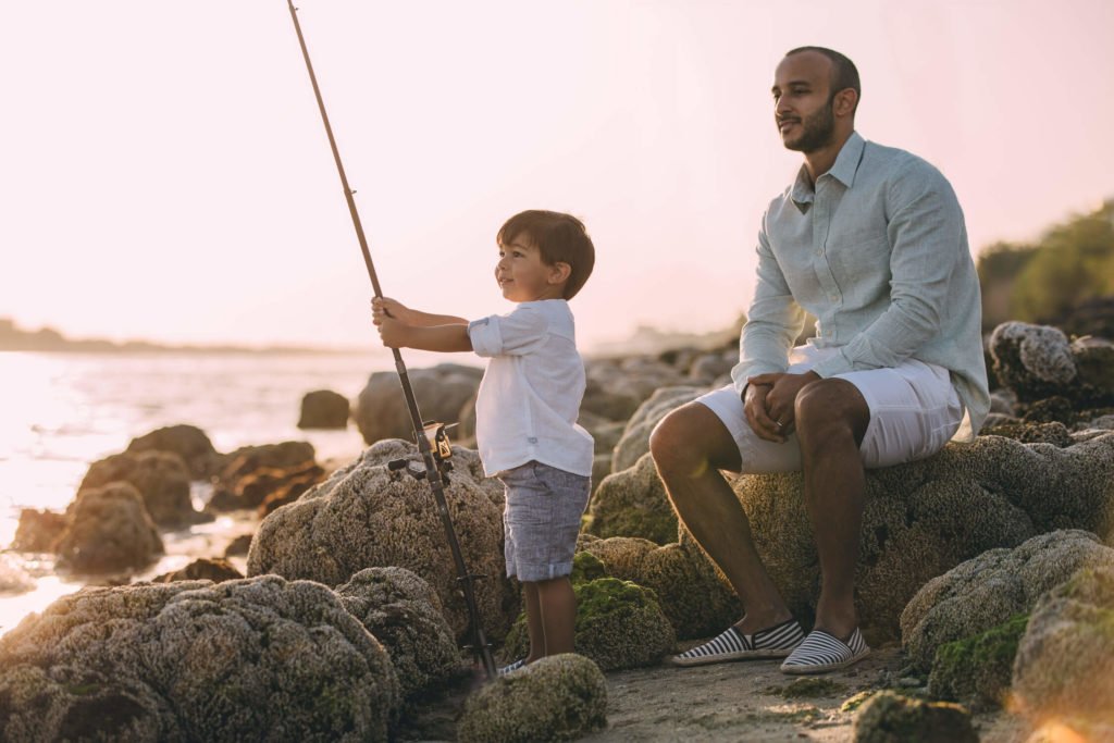 Dad proudly looks at his little boy while he is fishing in Abu Dhabi and Dubai