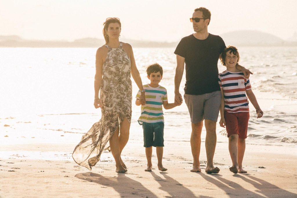 Mum, dad and two boys having a walk during sunset at the beach in Dubai and Abu Dhabi