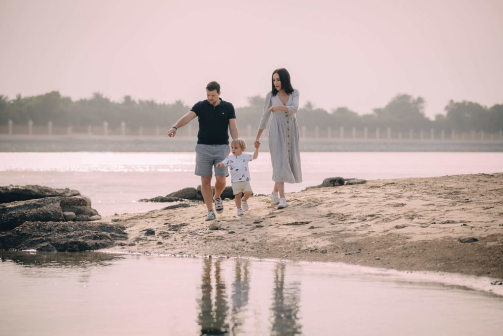 Mum, dad and their toddler having a walk near the water in Dubai and Abu Dhabi