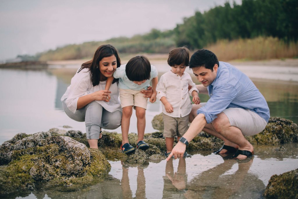 Mum, dad and their two boys looking for fish in the pond in Abu Dhabi