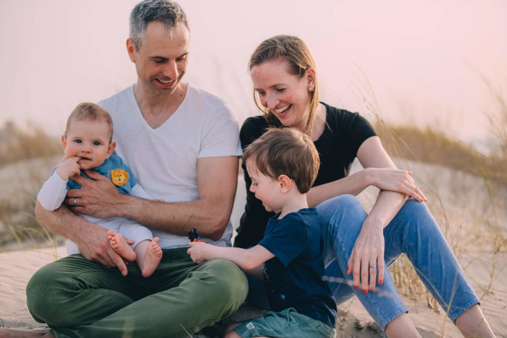 In the beach of Abu Dhabi a boy is showing their parents his car, while dad holds his baby brother.