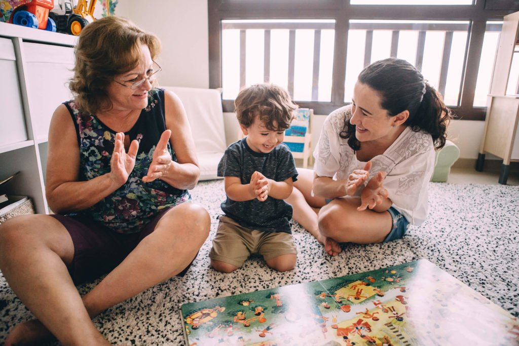 In Dubai a grandmother, mother and boy are happy and clapping while they also read a book