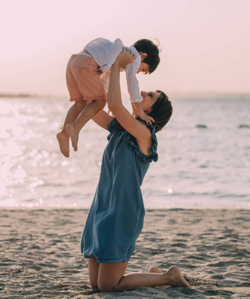 A mum holding her boy up in the air at the beach in Abu Dhabi
