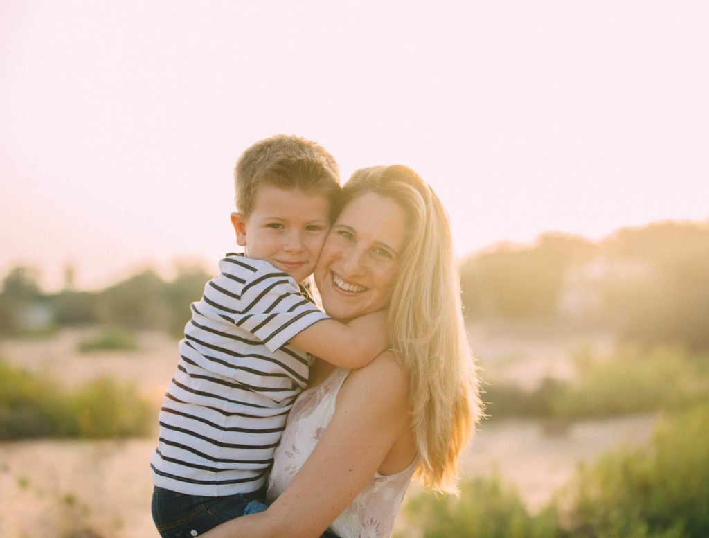Backlit image of a mother carrying her boy in a park of Dubai