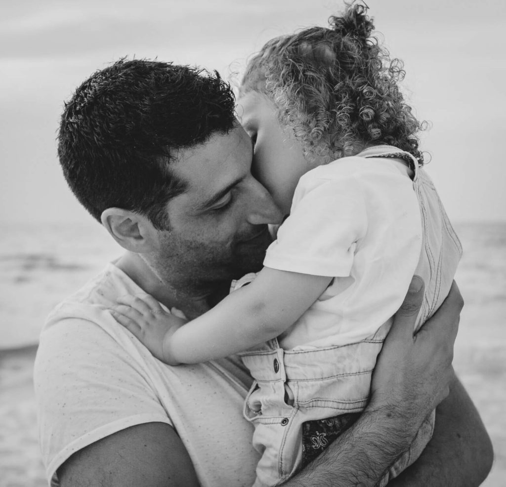 In the beach in Dubai a little boy kisses his dad. Dubai family photographer