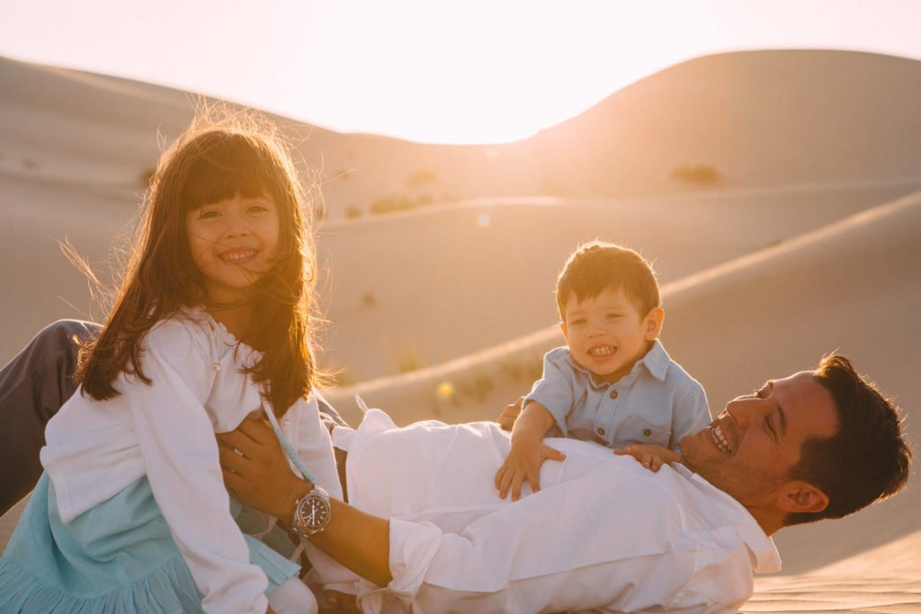 Dad playing with his kids in the sand dunes in Dubai