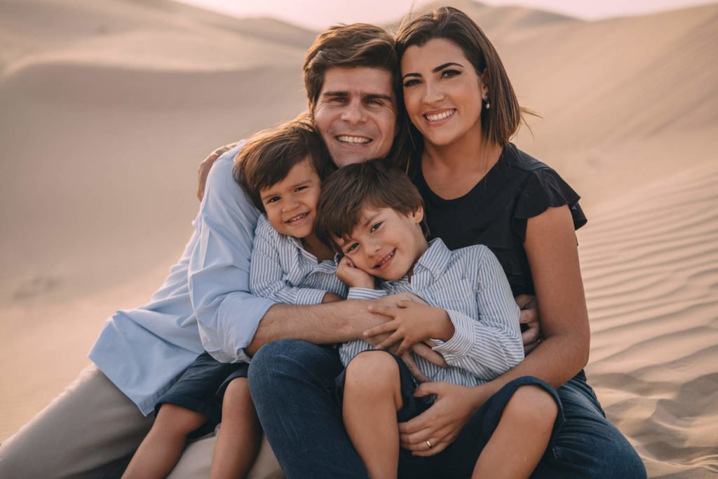 Portrait of a family, mum, dad and two little boys in the sand dunes of Dubai and Abu Dhabi