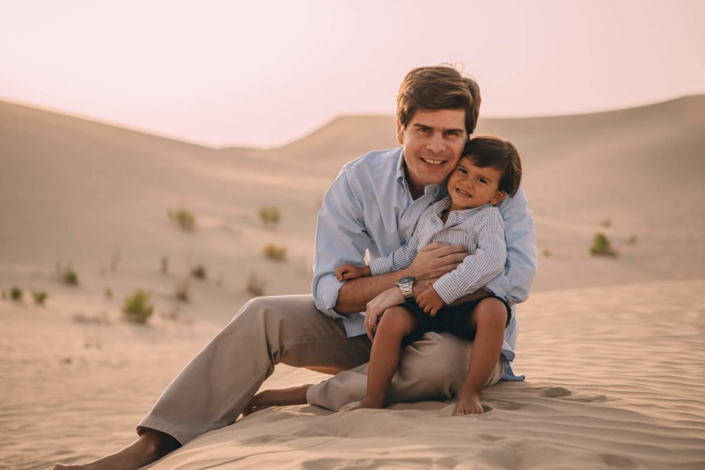 Portrait of a dad with his little boy in the sand dunes of Dubai