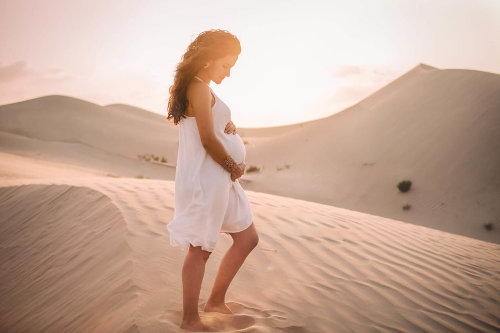 Dubai maternity photographer: A young mother to be standing in the sand dunes