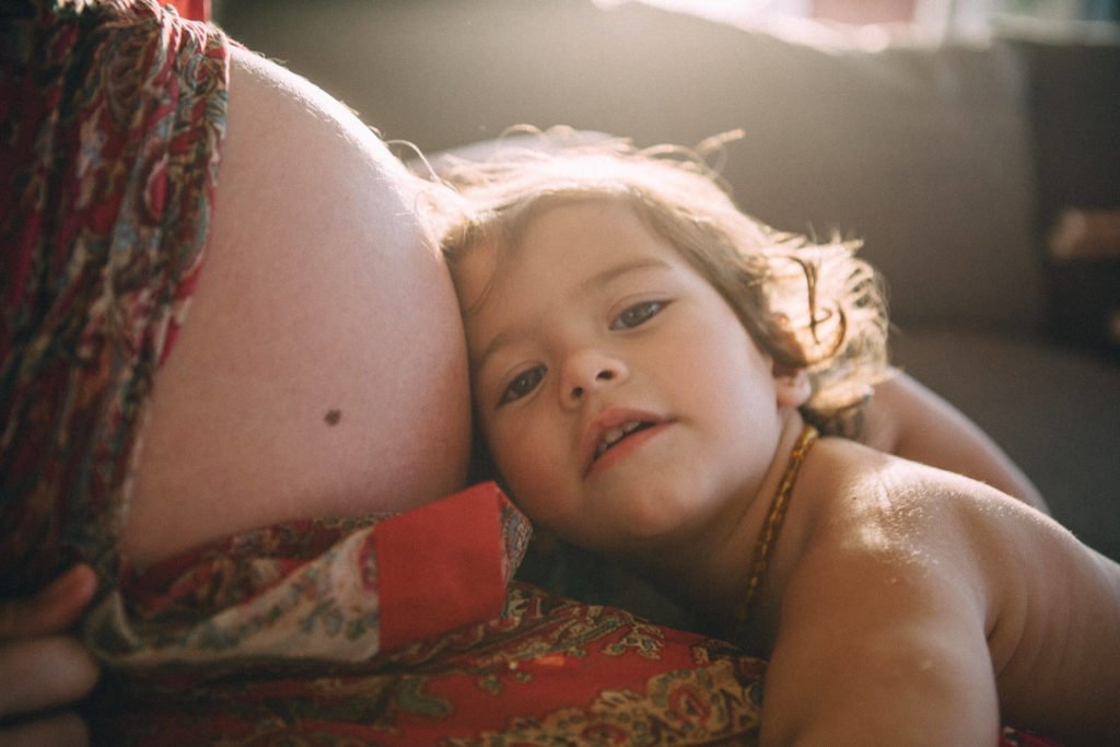 A little girl leans on her mum´s pregnant belly. Dubai maternity photography