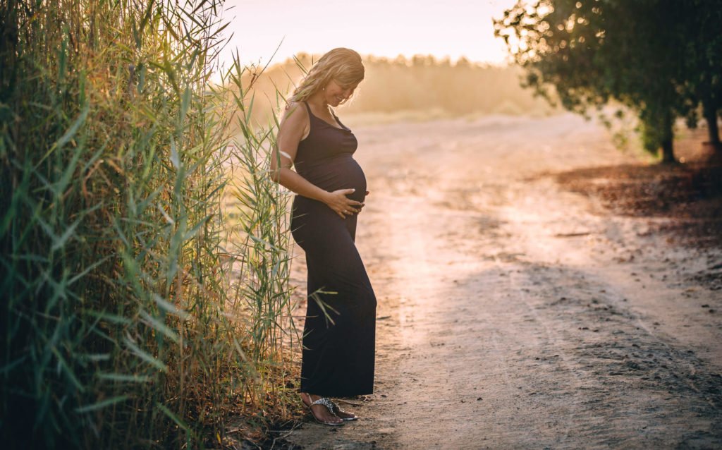 A pregnant woman wearing a blue maternity dress in a Dubai beach