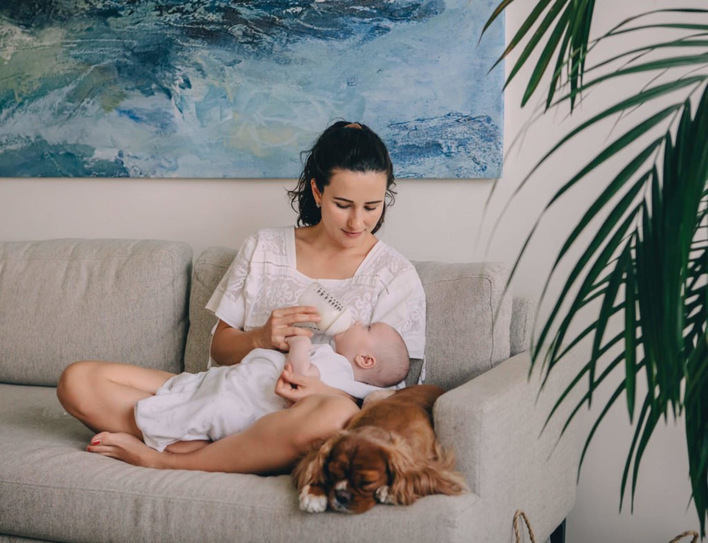 Beautiful newborn session in Abu Dhabi: a mother feeds her baby with her dog by the side