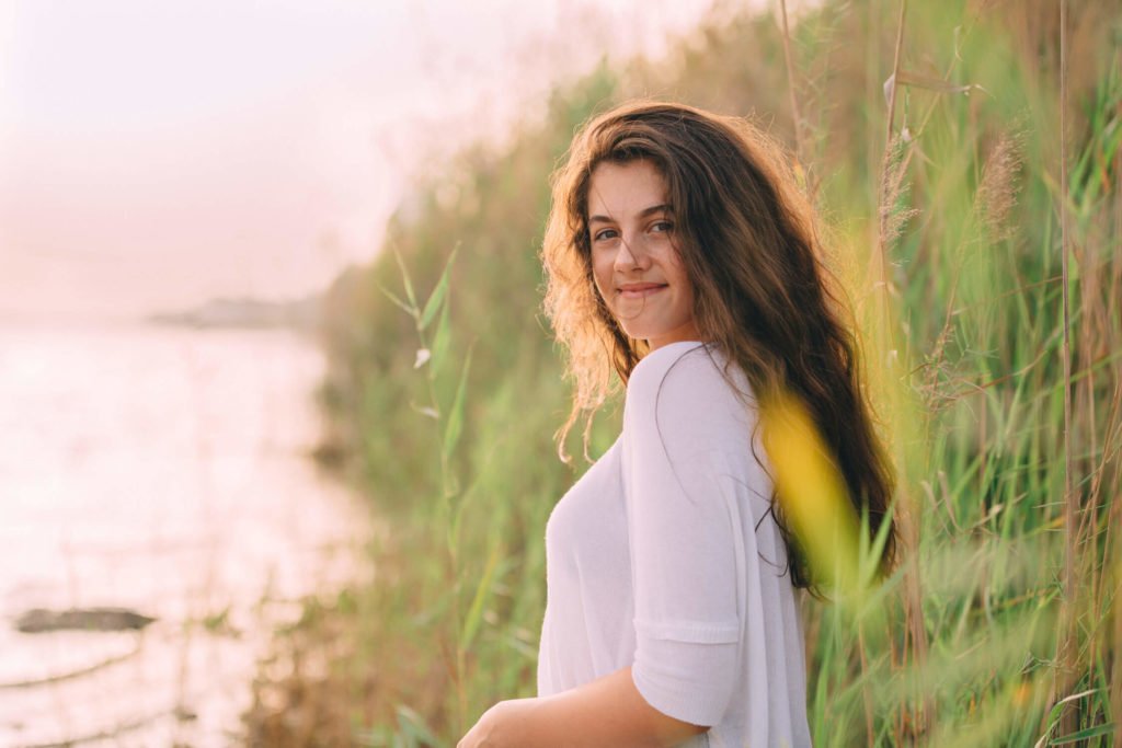 A teenager smiles at her photographer in the beach of Dubai