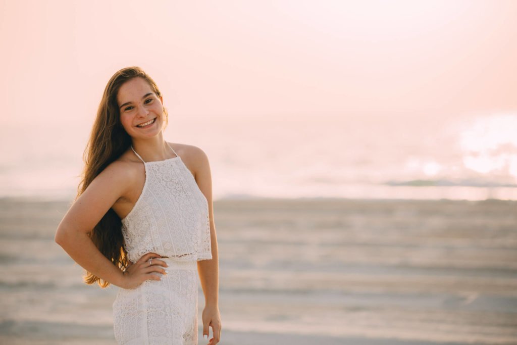 A teenager smiles at her photographer in the beach of Abu Dhabi