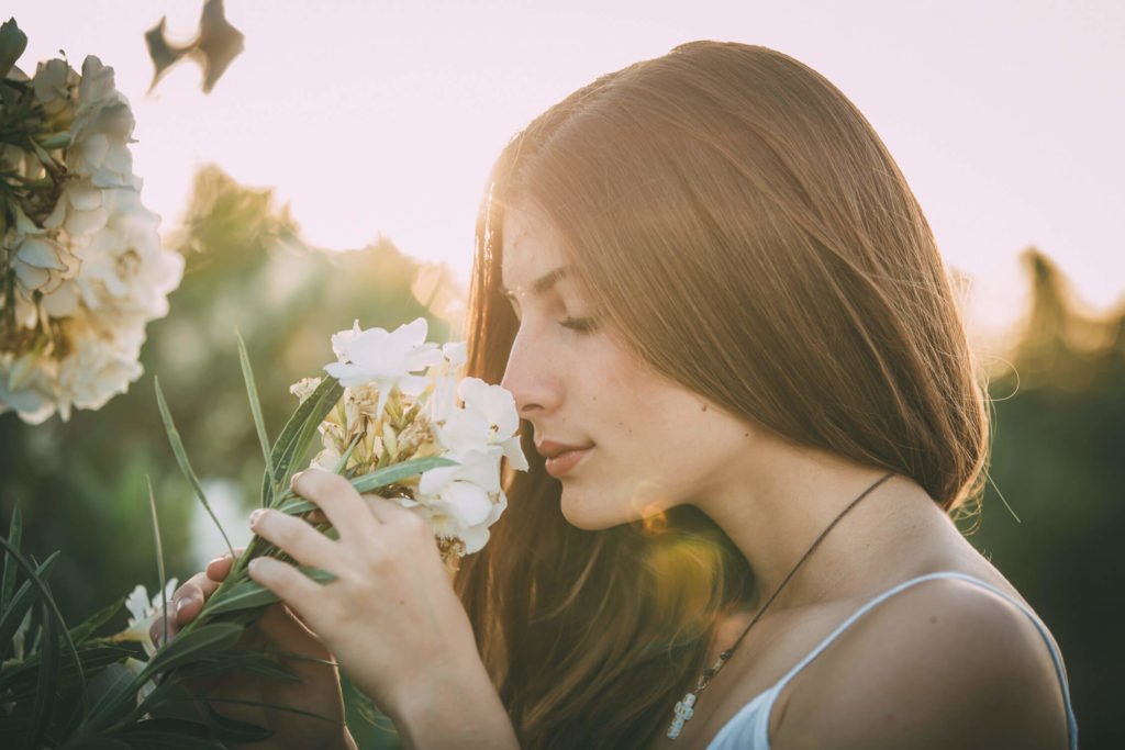 A gorgeous teenage girl smells the scent of a flower