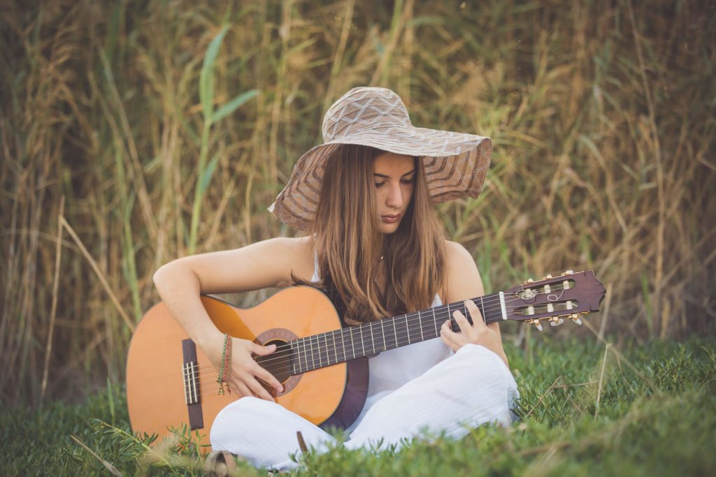 A high school girl wearing a boho hat plays the guitar in Dubai and Abu Dhabi