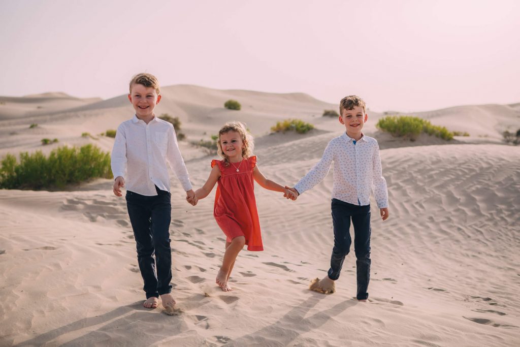 Farewell to the Dubai and Abu Dhabi desert. Three kids walking in the sand dunes of Abu Dhabi