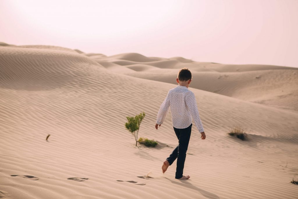 Farewell to the Dubai and Abu Dhabi desert. A boy walking in the sand dunes of the Arabian desert