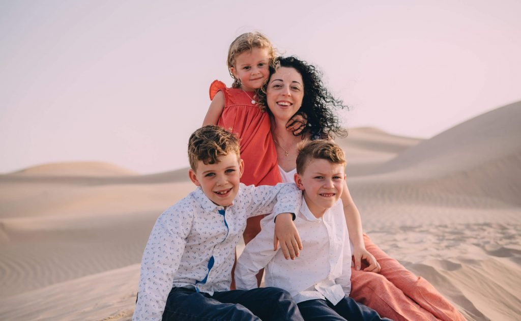 Portrait of a mum and her three kids in the sand dunes of Abu Dhabi