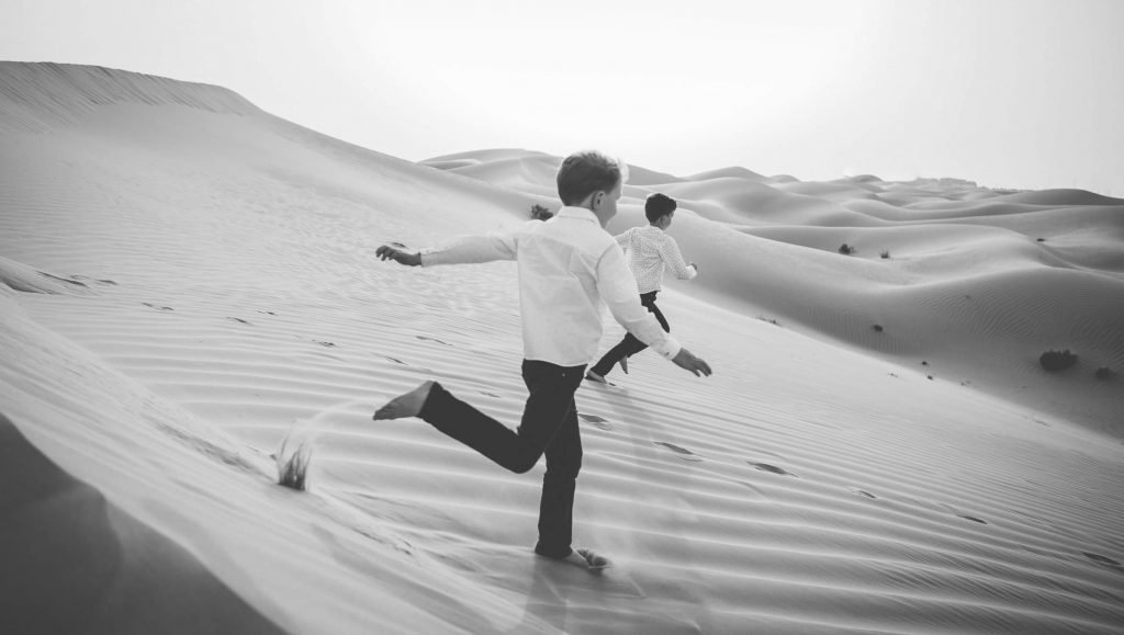 Farewell to the Dubai and Abu Dhabi desert. Boys running in the sand dunes of Abu Dhabi