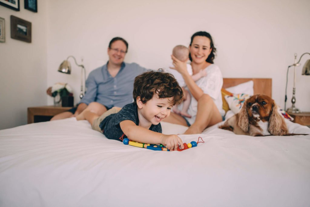 In-home lifestyle family session. A family and their dog sitting in their bed