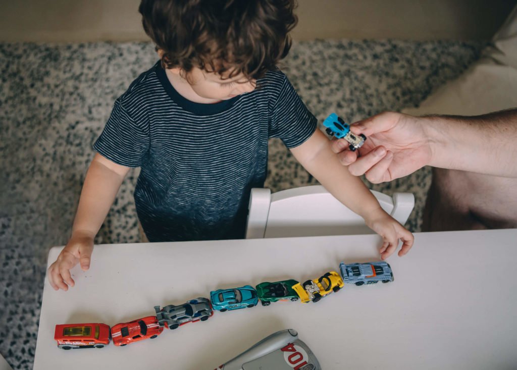 In-home lifestyle family session. A little boy put his cars in a line as if they were a train