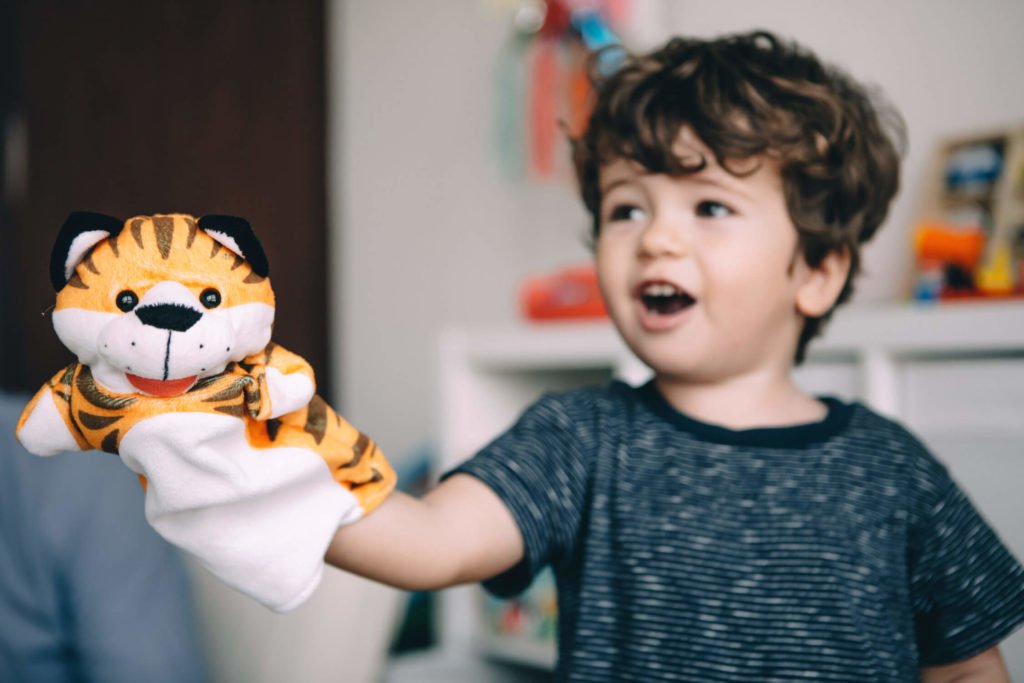 A little boy plays with his tiger puppet