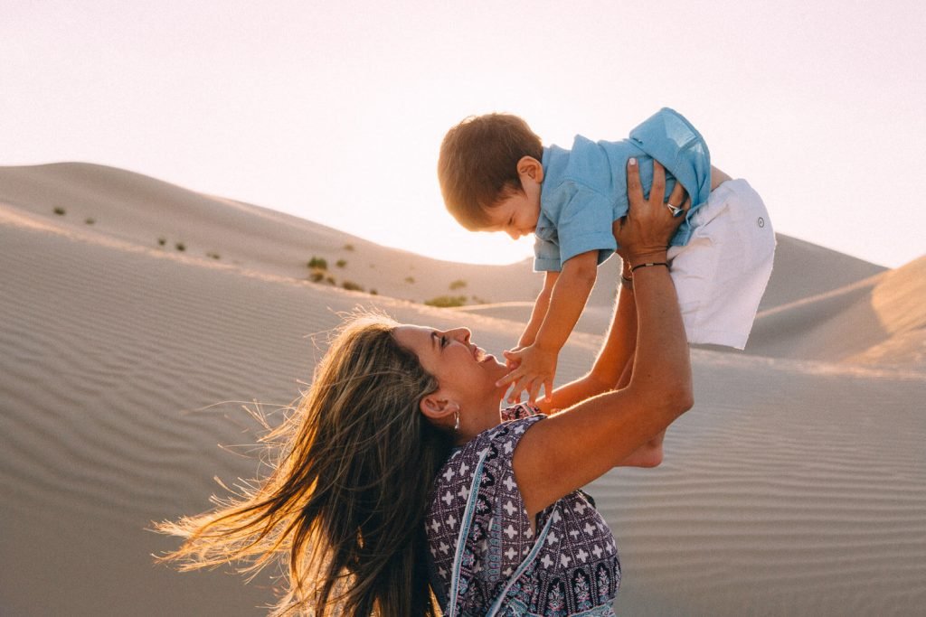 Desert photo shoot in Abu Dhabi. Mum carrying her little boy in the desert