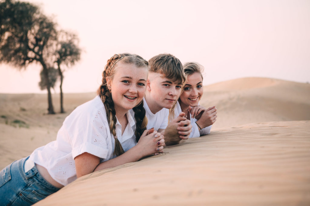 Portrait of three teenagers in the desert of Dubai at sunset